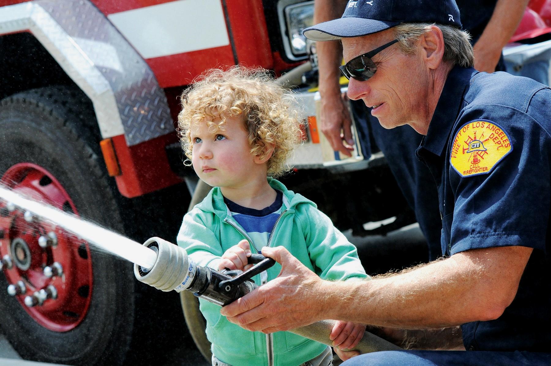 Matt teaching a child to use a fire hose